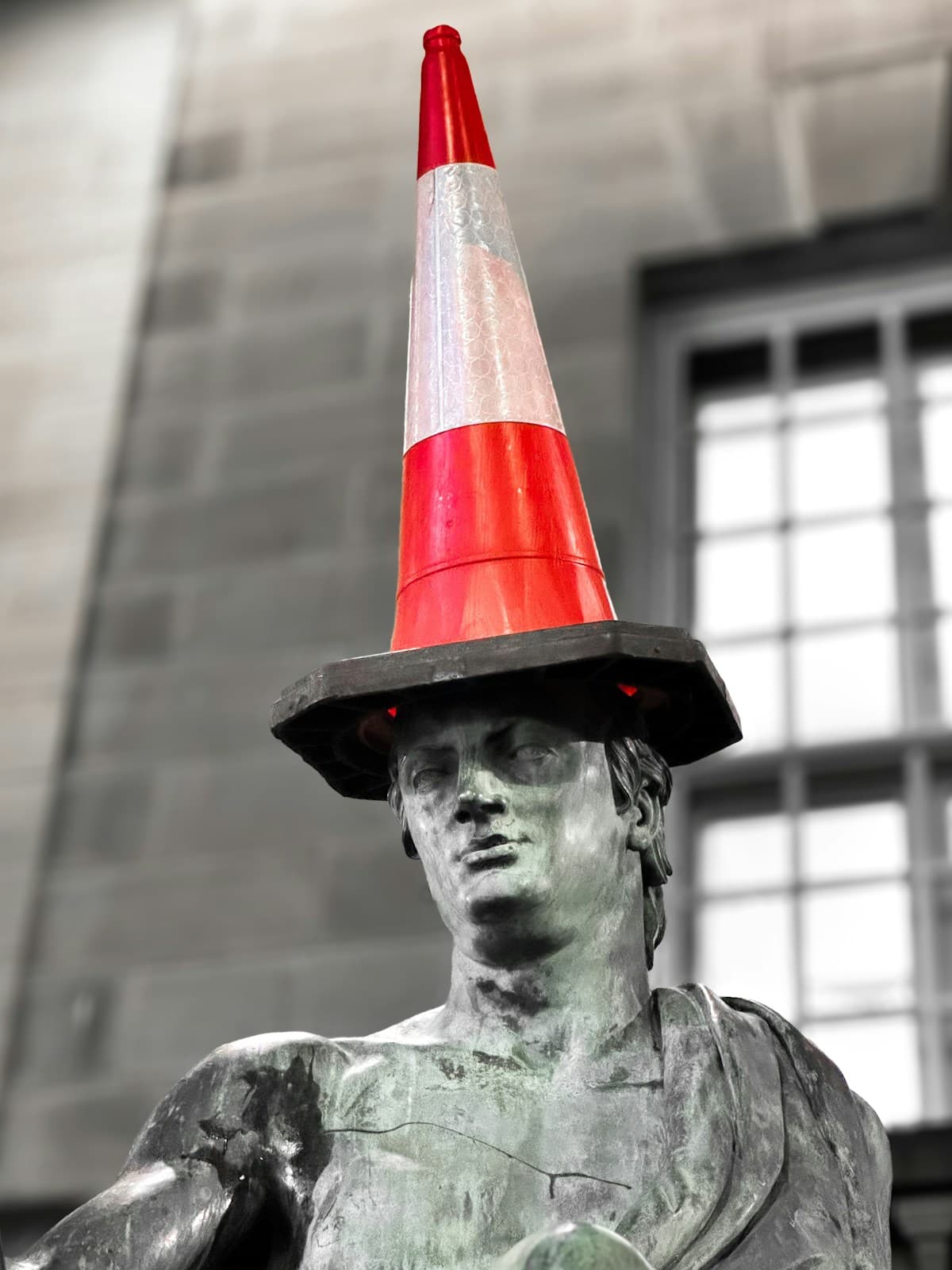 A stone statue wearing an orange traffic cone